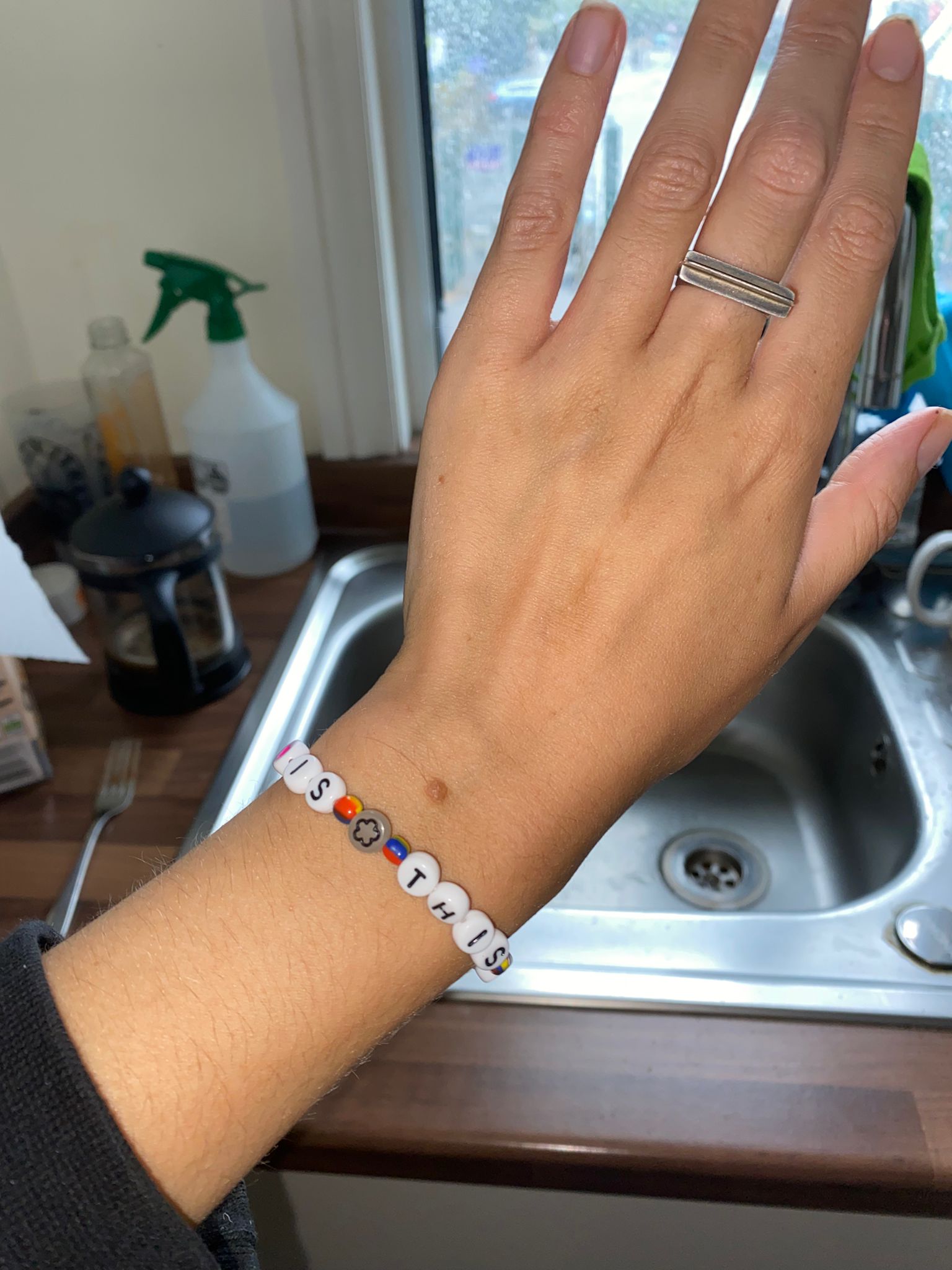 Is This It bracelet being modelled on a hand next to a sink